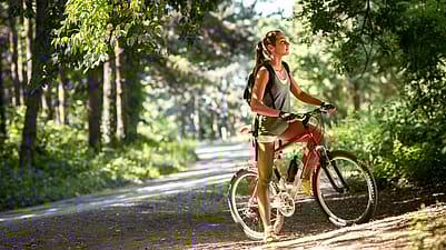 Frau faehrt im Wald Fahrrad