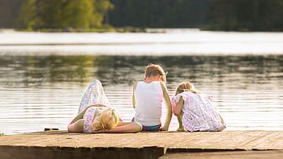Mutter entspannt mit ihren zwei Kindern am Seeufer