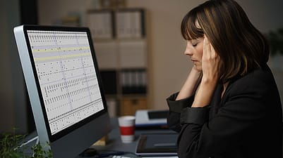 Frau mit Kopfschmerzen vor dem Laptop