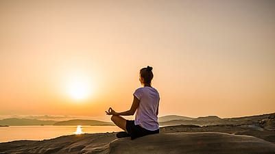 Frau macht Yoga in der freien Natur beim Sonnenuntergang
