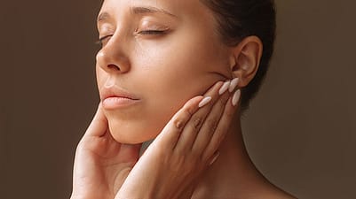 Woman with eye closed moisturising her face
