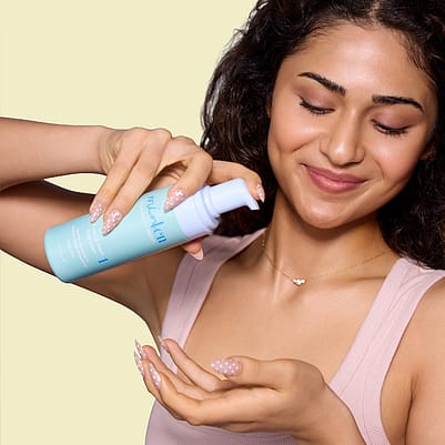 Frau hält Produkt vor Gesicht und trägt es auf