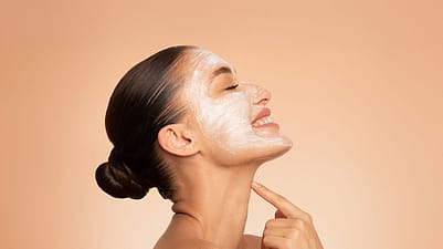 smiling woman applying creme on her face