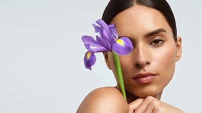 Model holds an iris flower in front of her face