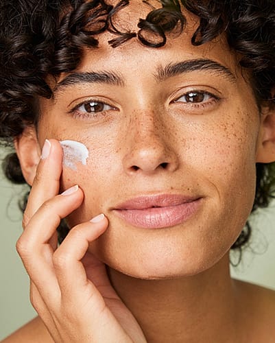 Woman applying face moisturiser