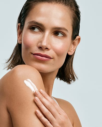 Woman applying moisturiser to shoulder