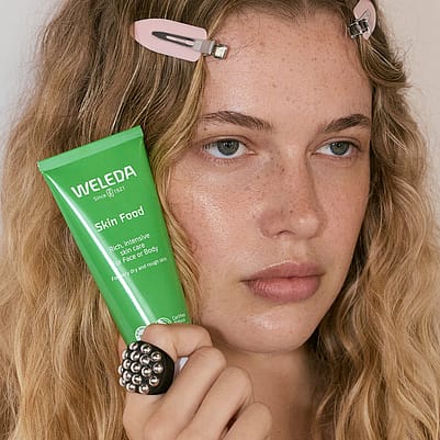 Weleda Skin Food Original helf by blonde model by her face.