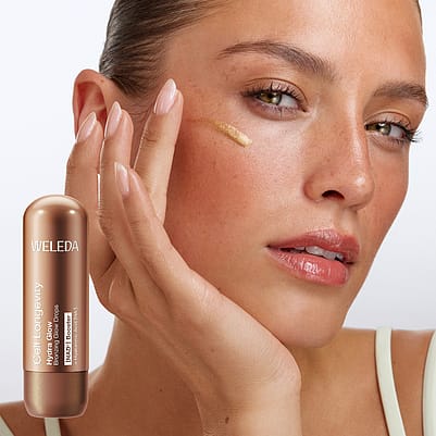 Frau trägt Hydra Glow Bronzing Glow Drops auf Wange auf