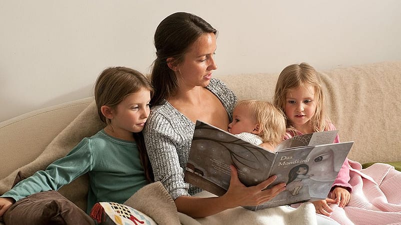 Mamma a letto con tre figli legge una storia da un libro