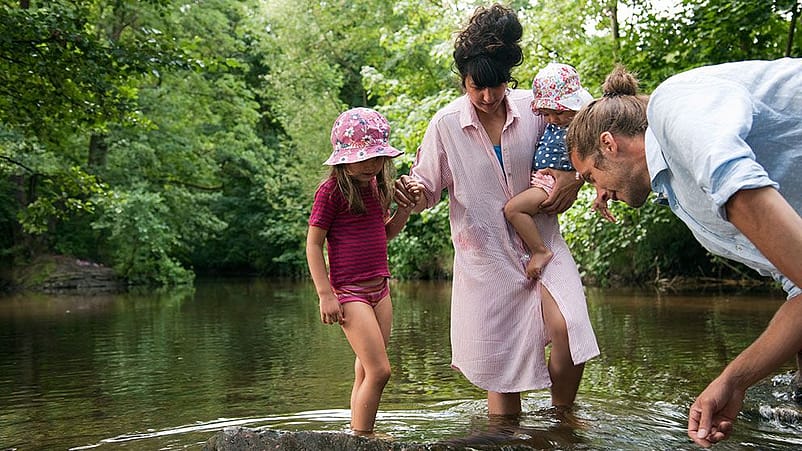 Famiglia con piedi e gambe nel laghetto guardano il fondo dell'acqua