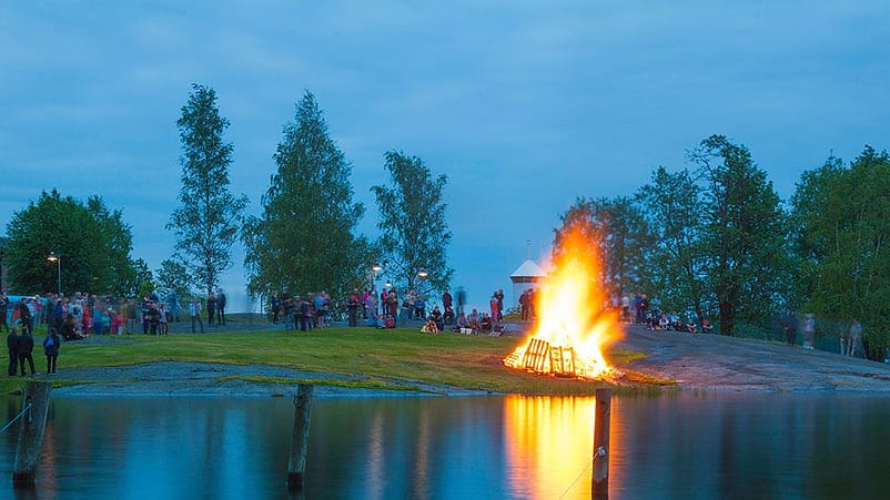 Falò vicino al lago e folla di persone intorno