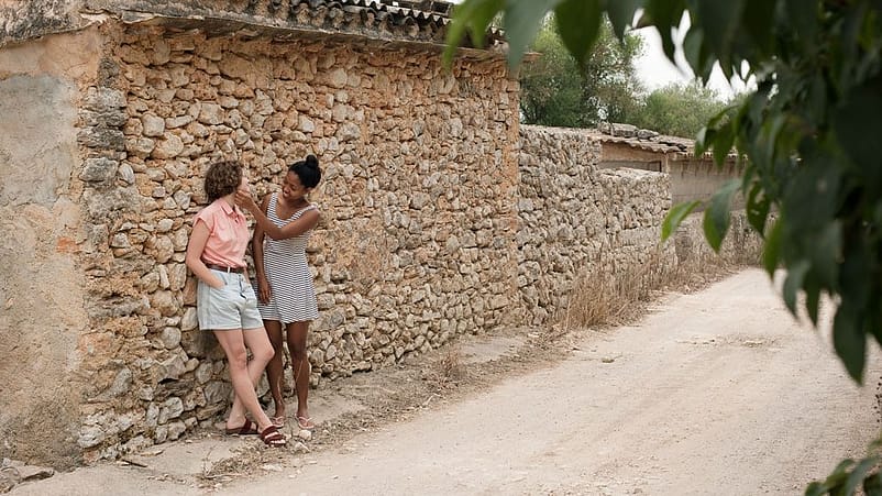 strada con due ragazze vicine ad un muro di pietra