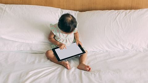 Kind sitzt vor einem Tablet Bildschirm