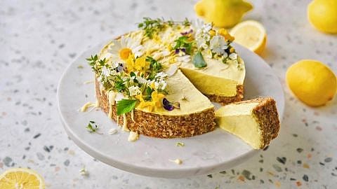 Zitronenkuchen mit Blüten und Zitronen auf einer Platte