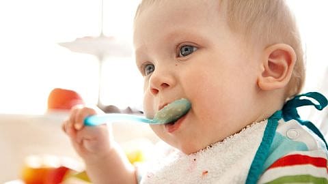 Bebé comiendo con una cuchara en la mano