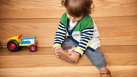 niño poniendose los zapatos sentado en una escalera con un juguete al lado