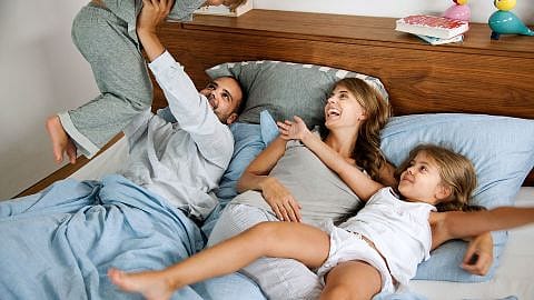 Madre junto a sus hijos durmiendo en una cama