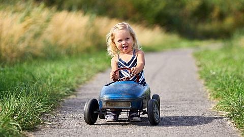 niña montada en un cochecito de juguete