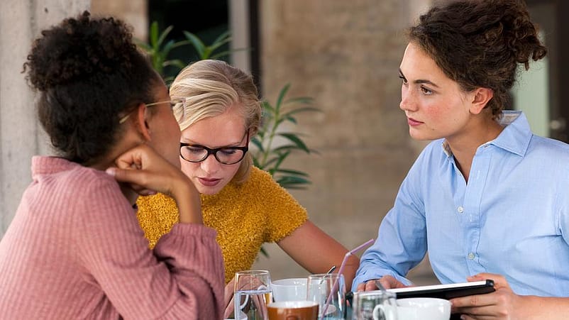 trois femmes sont assises à une table