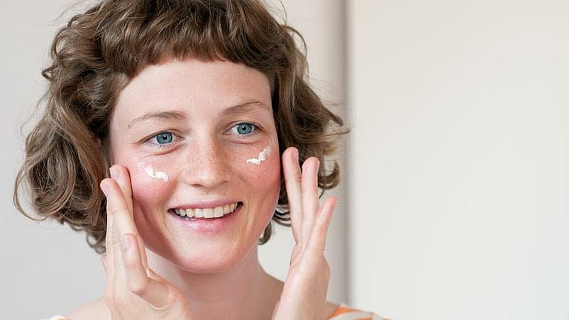 Una giovane donna applica la crema sul suo viso