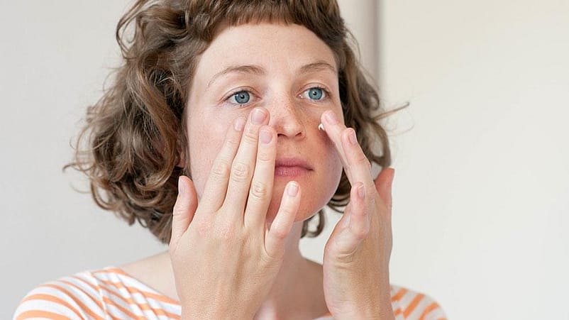 Una giovane donna applica la crema sul suo contorno occhi