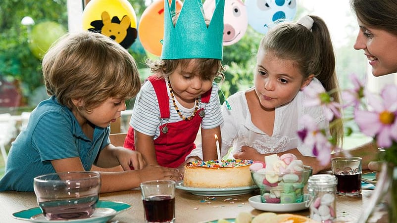niños celebrando alrededor de una mesa, donde hay una tarta