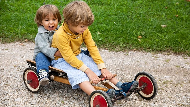 niños montados en un cochecito de juguete mientras juegan