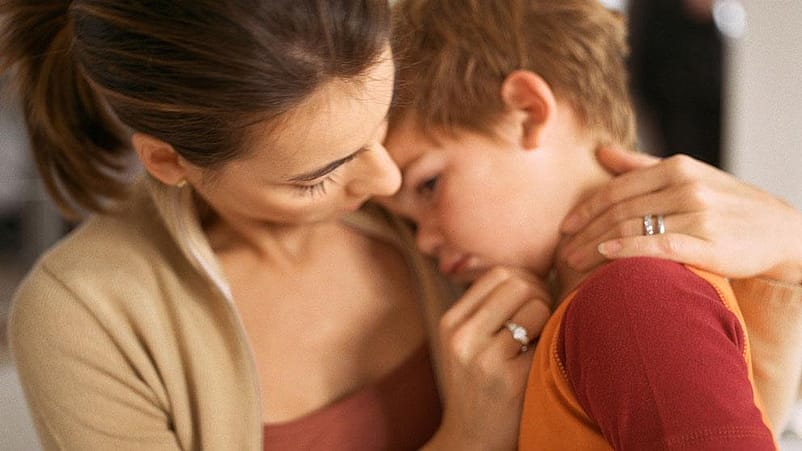 niño enfadado abrazado a su madre