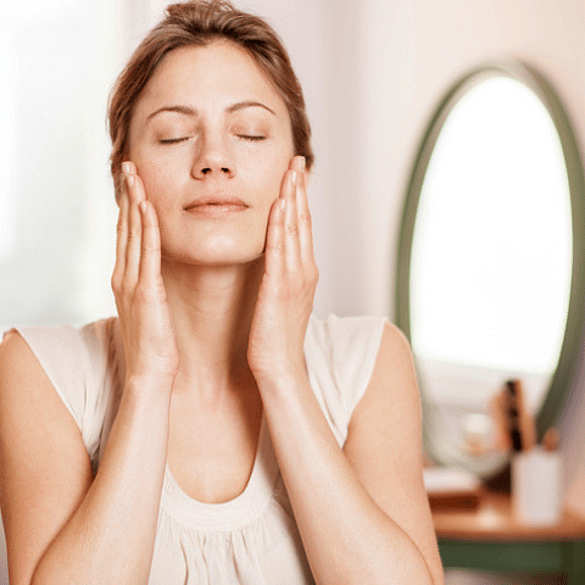 mujer aplicándose crema en el rostro