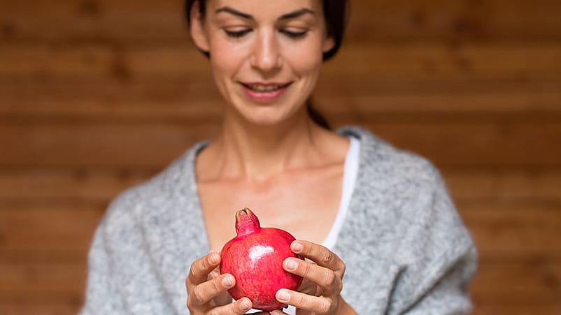 Donna tiene in mano melograno