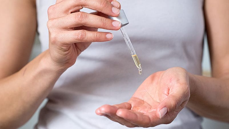 Droppar olja i handen med en pipett