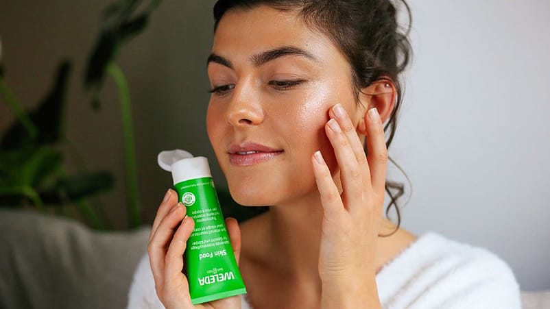 Junge Frau trägt Weleda Skin Food als Highlighter auf