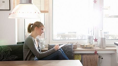 Frau auf dem Sofa macht sich Notizen