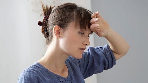 Frau hält sich den Kopf