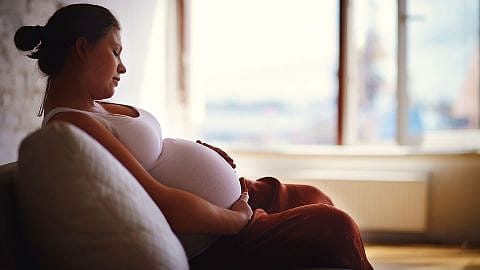 Schwangere legt Hand auf Bauch