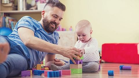 hombre y bebé sentados en el suelo jugando