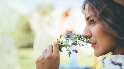 mujer oliendo flores