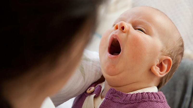 mujer con un bebé en brazos que está bostezando