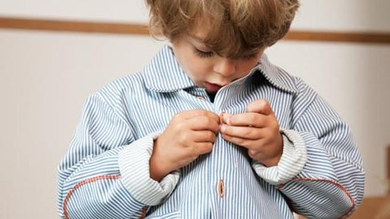 niño abrochándose la ropa