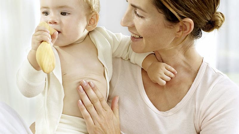 mujer mirando al bebé que tiene cogido en brazos envuelto en una toalla