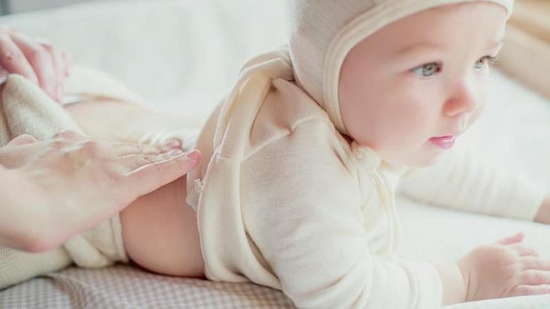 bebé tumbado boca abajo con un gorrito en la cabeza