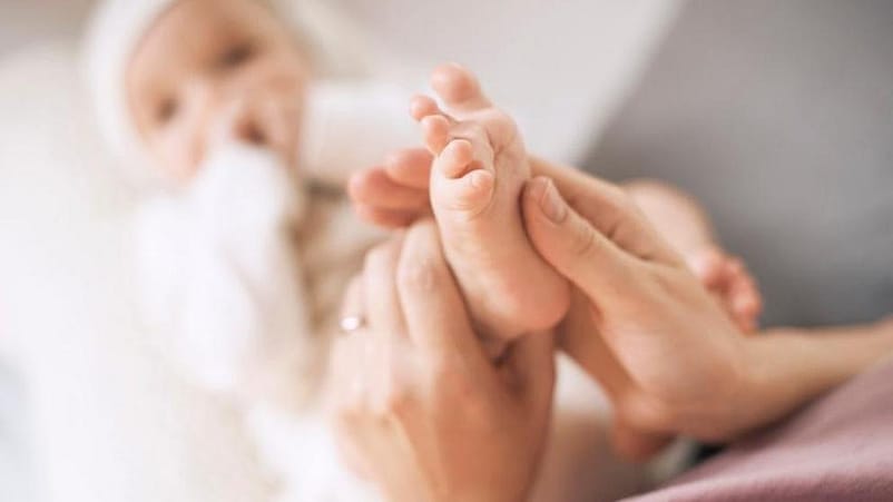 mujer haciendo un masaje a los pies del bebé