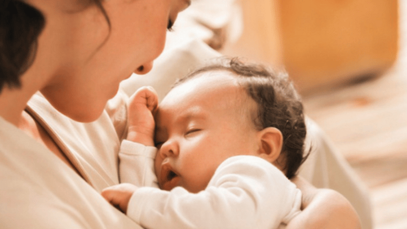 mujer sosteniendo a un bebé dormido en los brazos
