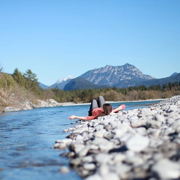 Frau liegt entspannt am Fluss