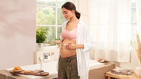 mujer embarazada aplicandose balsamo antiestrias de weleda en la tripa