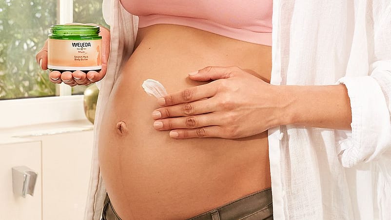 Kvinna smörjer in sin gravida mage