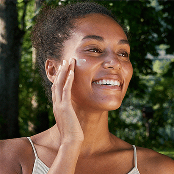 woman applying face lotion in nature