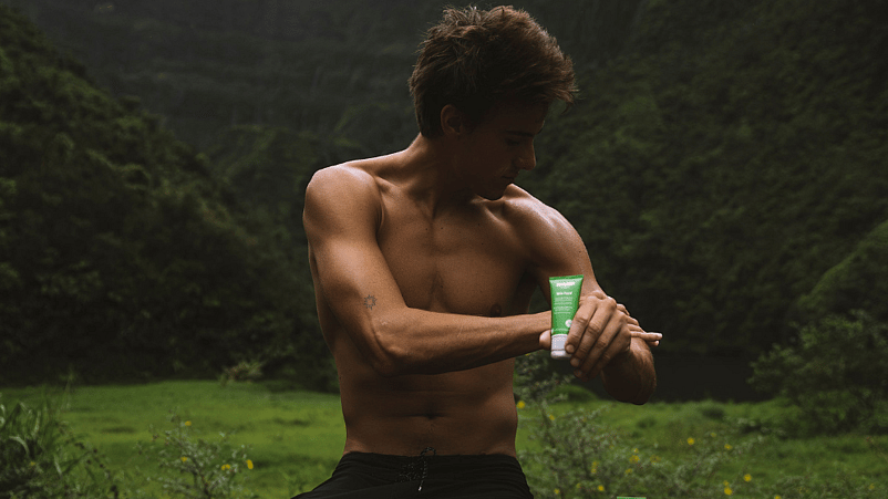 hombre aplicandose la crema Skin Food de Weleda en mitad de la naturaleza