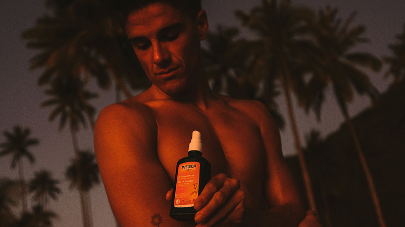 hombre aplicandose el aceite para masaje de árnica en mitad de la naturaleza