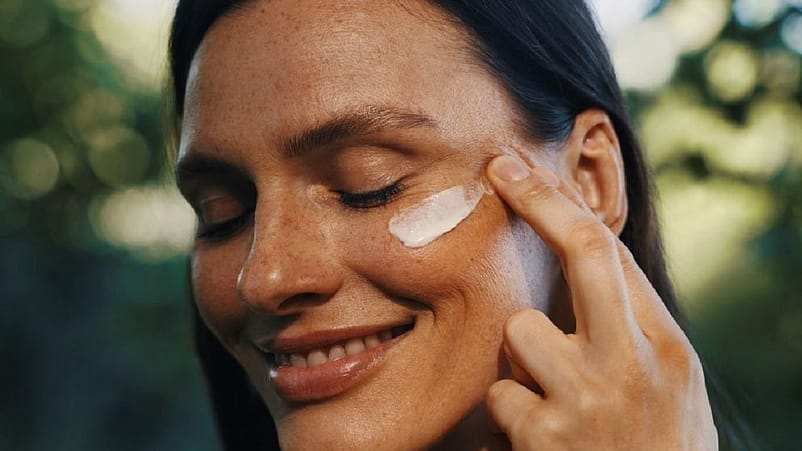 femme qui s'applique de la crème sur la joue